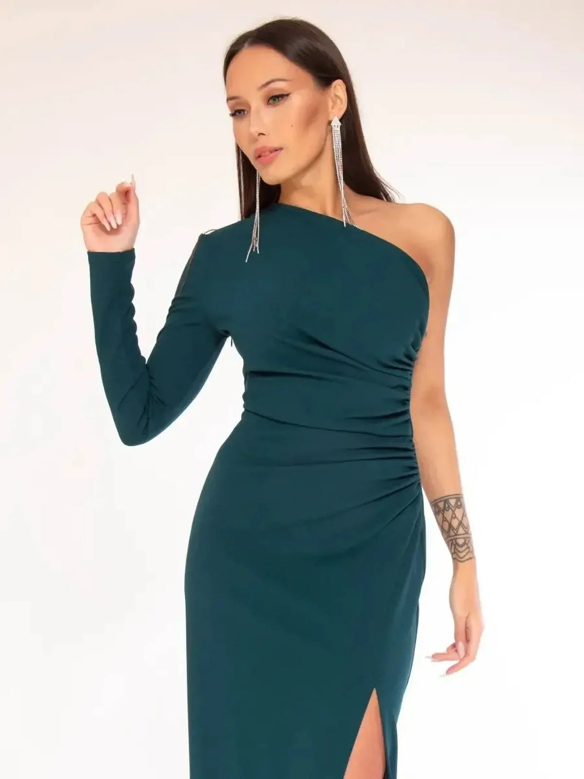 Model wearing the Maxi Dress Obsidian, featuring a one-shoulder design and a high leg slit in rich emerald green.