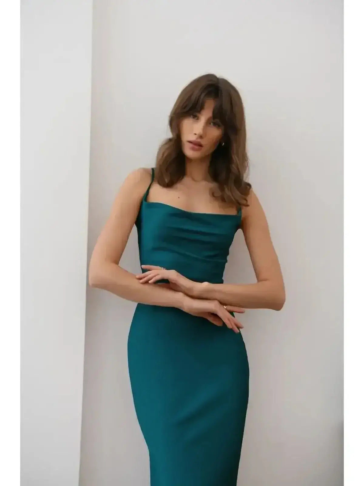 Woman wearing the Allure Midi Dress in emerald green, showcasing its sleek silhouette and satin shine.