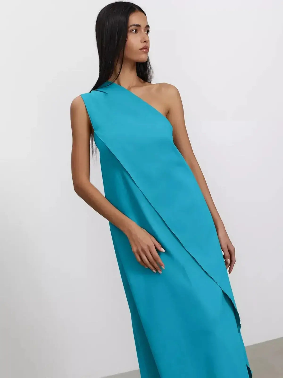 Model wearing Azure Sway Maxi Dress in vibrant turquoise showcasing a chic one-shoulder design and airy A-line silhouette.