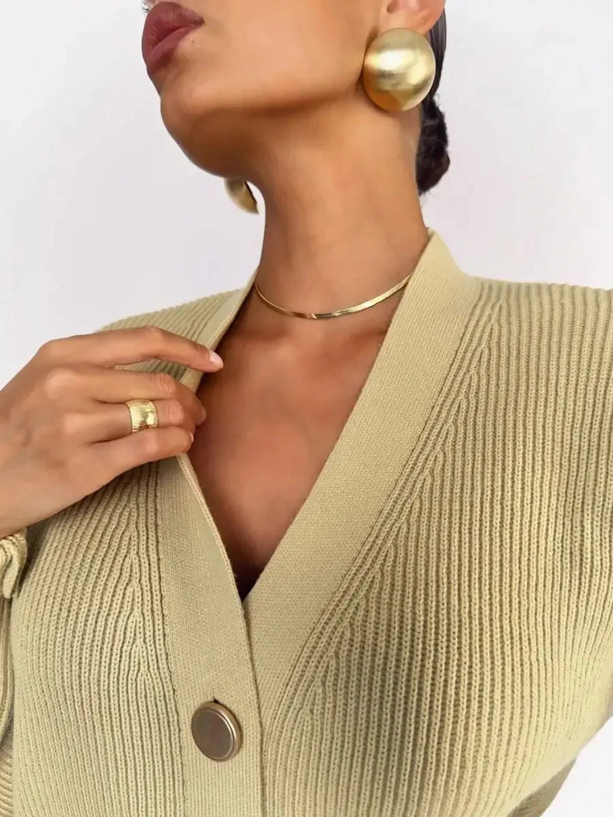 Celeste Cardigan by Lauven, showcasing a model in warm beige oversized knitwear with stylish gold accessories.