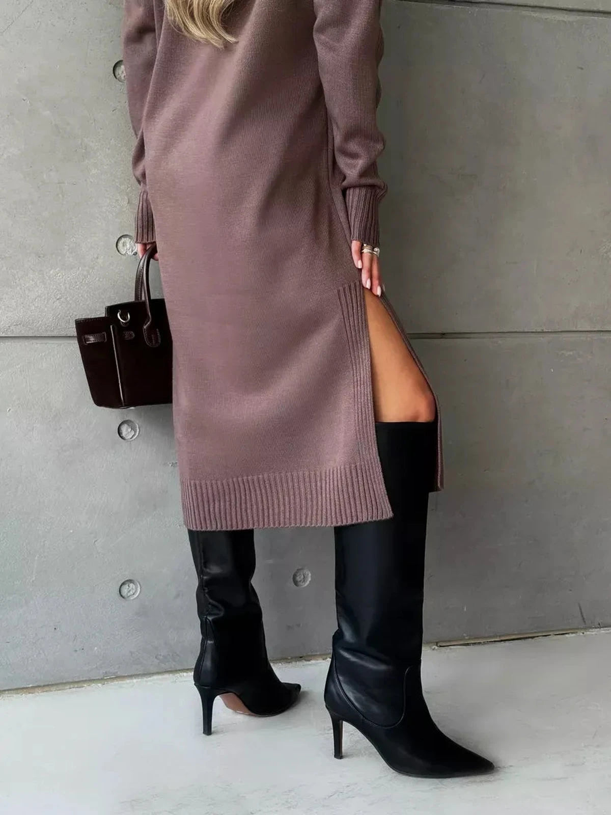 Back view of a model in the Noirra Midi Dress with high slit, styled with knee-high boots, showcasing modern knit sophistication.