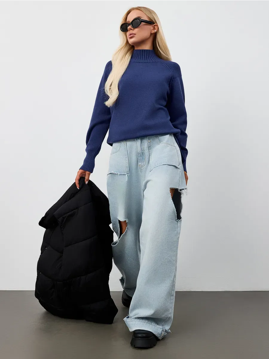 Indigo Sweater by Lauven showcased in an oversized navy blue cashmere knit with high neck, paired with light denim and a puffer jacket.