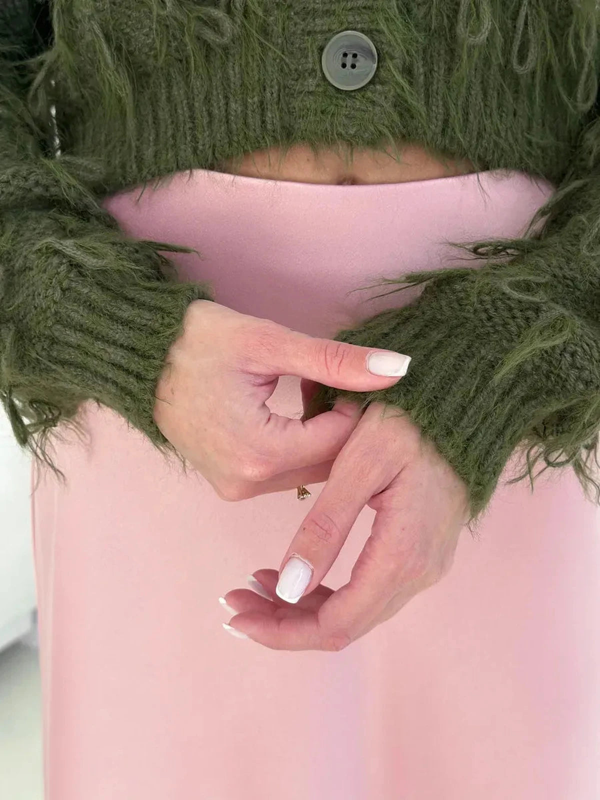 Olive Cardigan by Lauven featuring cozy cropped design and feathered fringe details, hands showing the textured knit sleeves.