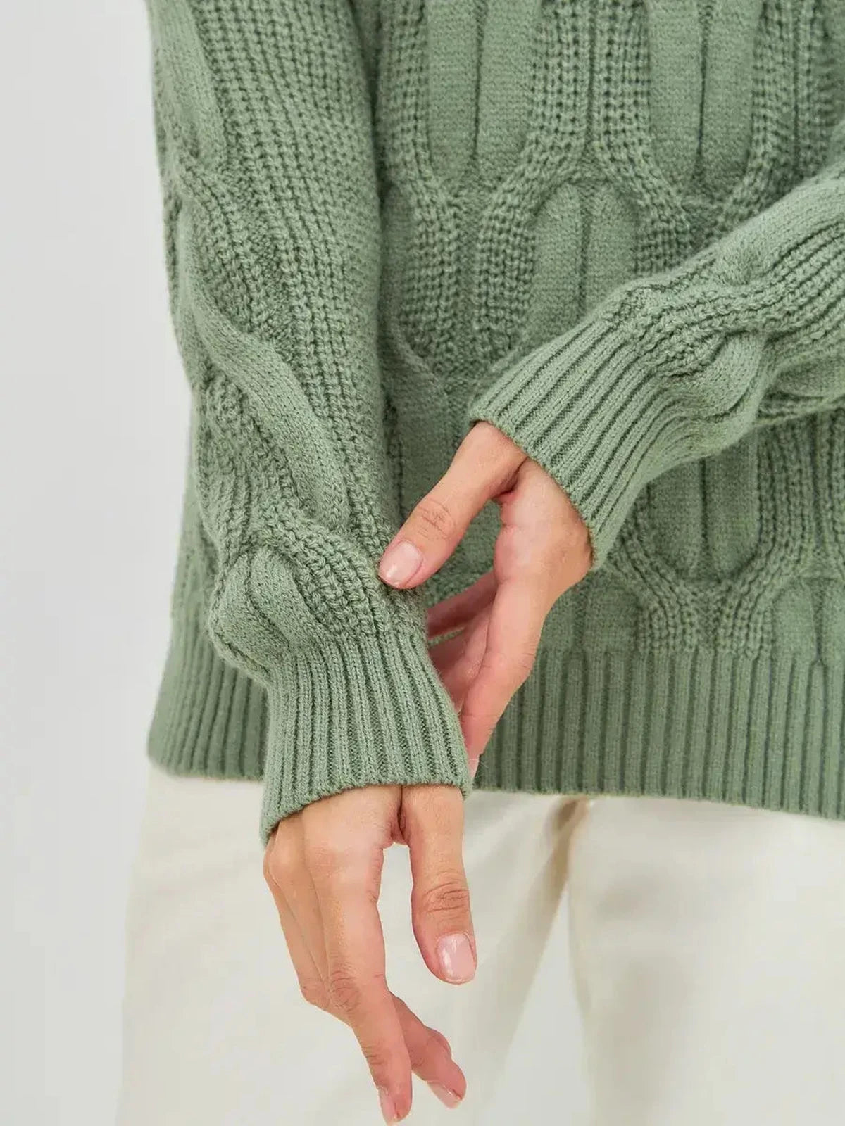Woman wearing an Ivy Sweater with oversized cable knit and high neck by Lauven, showing the sleeve detail.