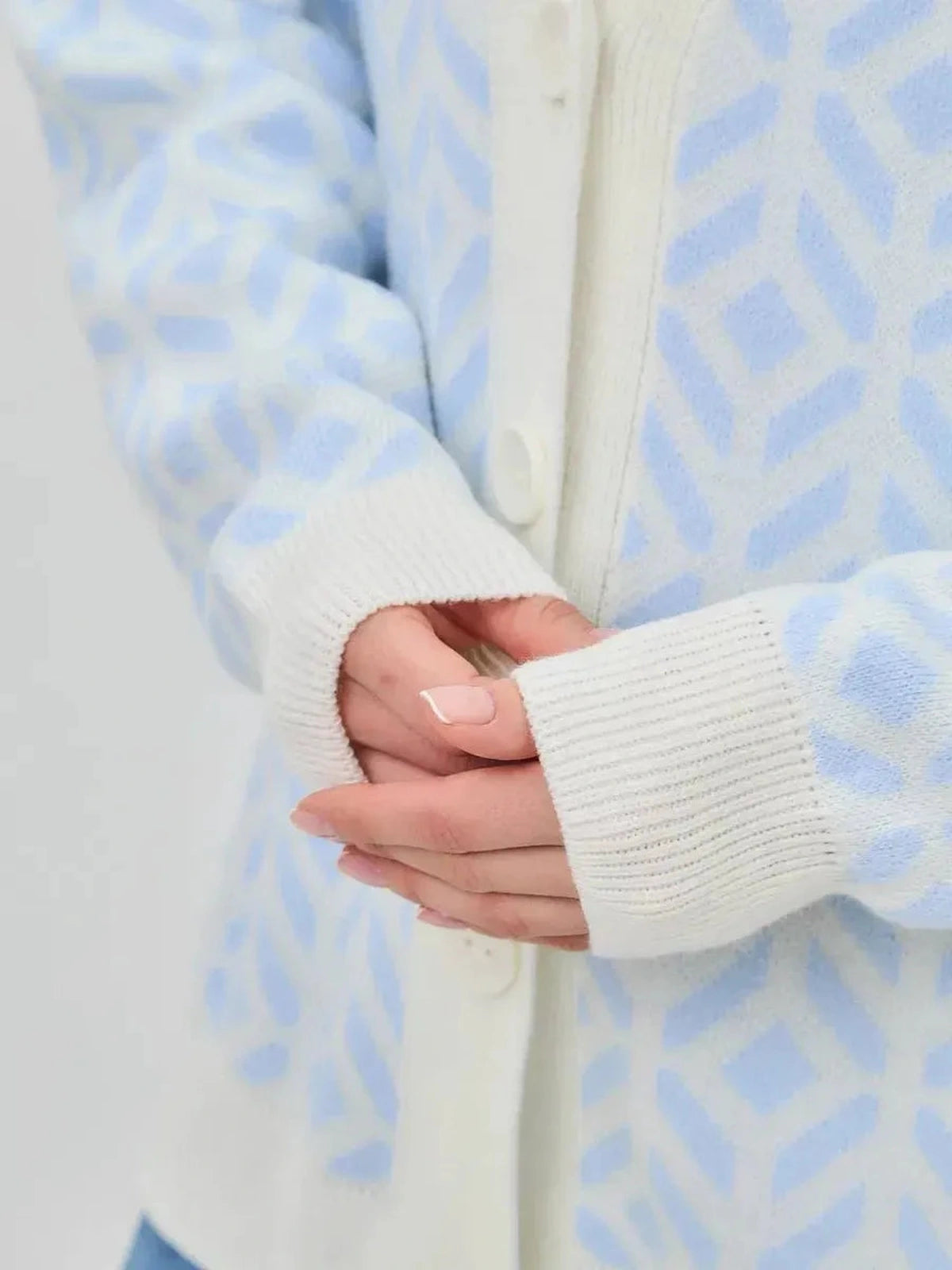 Close-up of hands wearing the Arika Cardigan in Milk Blue, featuring a relaxed fit and soft acrylic knit by Lauven.