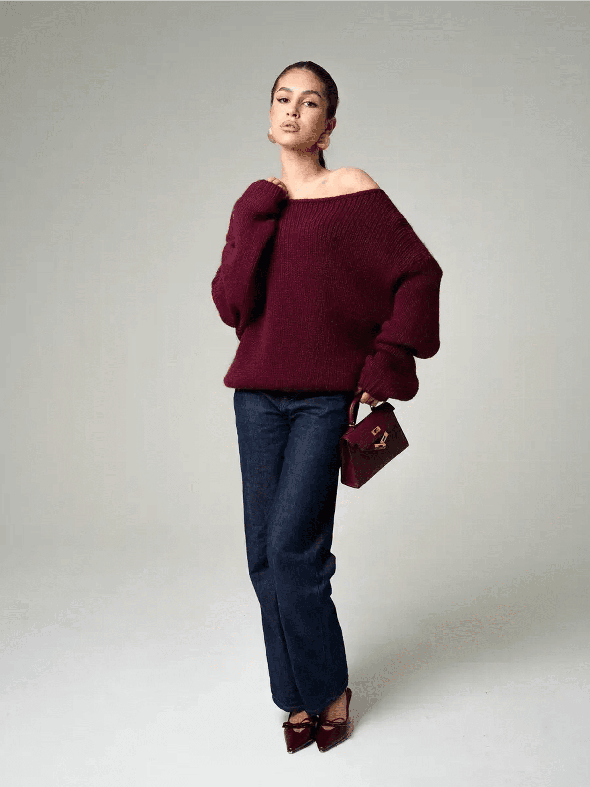 Model showcasing the Bordeaux Sweater by Lauven, an oversized off-shoulder knit in deep wine color.