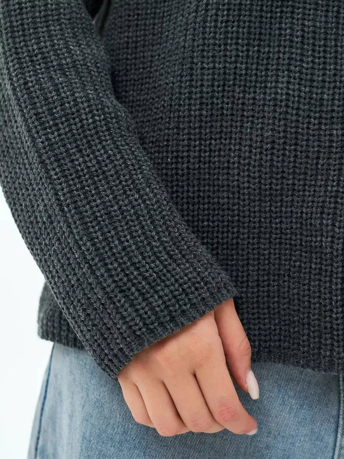Close-up of a hand wearing the Lauven Luna Sweater, showcasing the textured knit in charcoal gray.