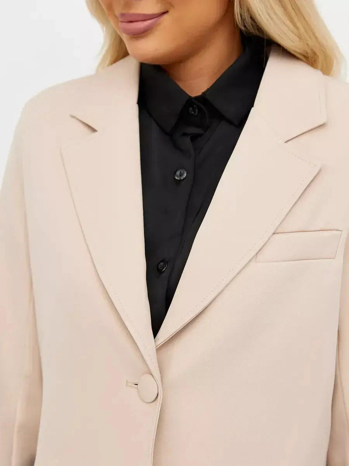 Close-up of a woman wearing a Lauven Sandstone Blazer in soft beige over a black shirt, showcasing classic tailoring.