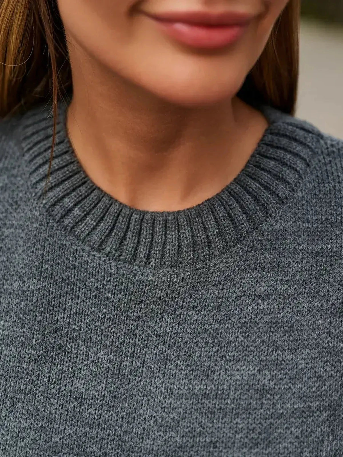 Close-up of a woman wearing a Slate Pullover by Lauven, showcasing the ribbed neckline and soft gray knit fabric.