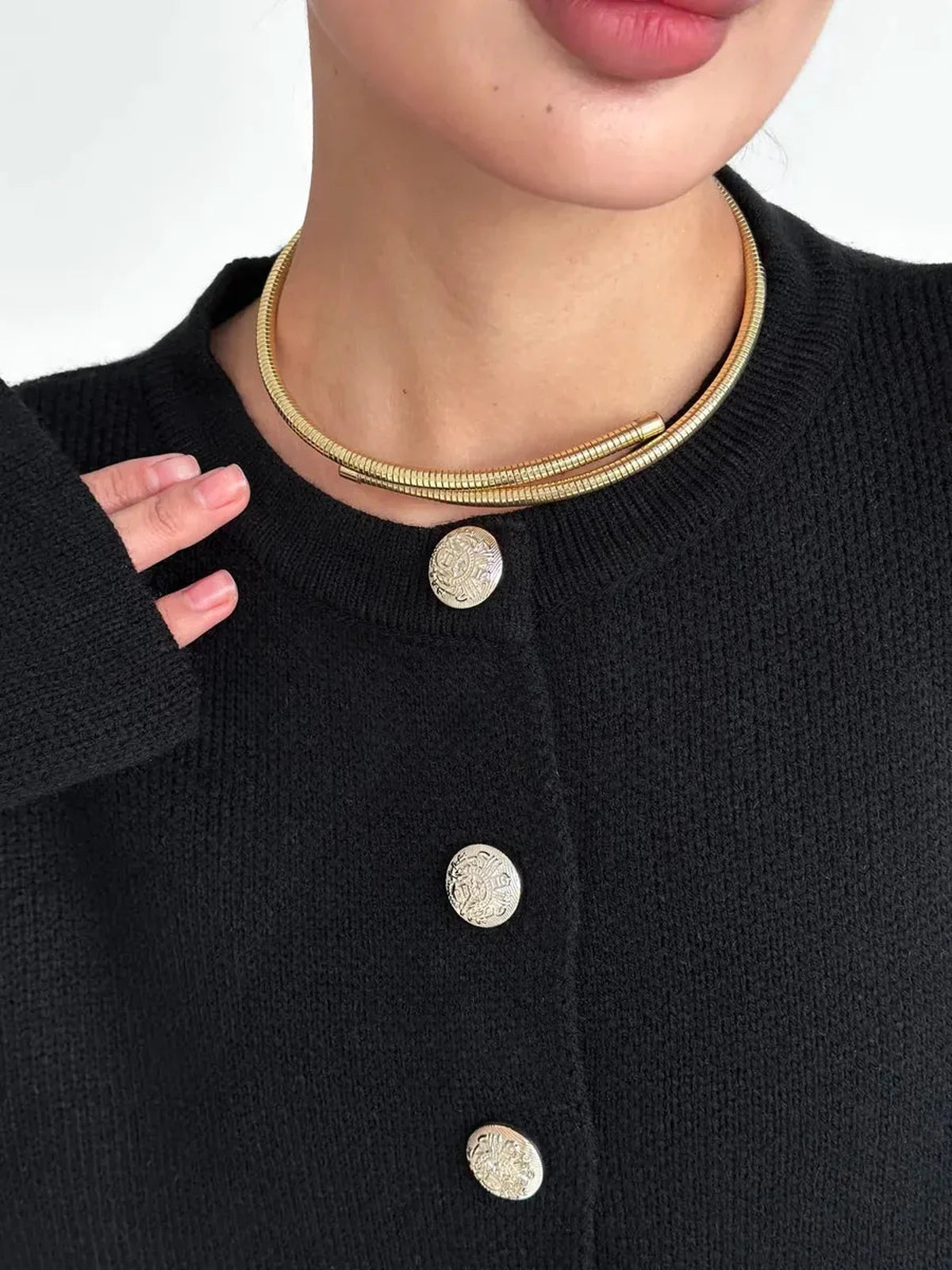 Close-up of a woman wearing the Noir Cardigan by Lauven, showcasing gold accessories and stylish buttons.