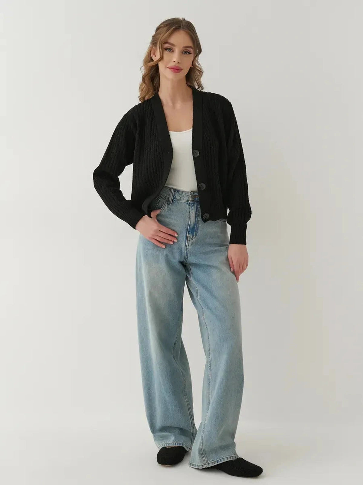 Model wearing the Noir Cardigan by Lauven, an oversized cropped knitwear piece in black with light blue jeans.