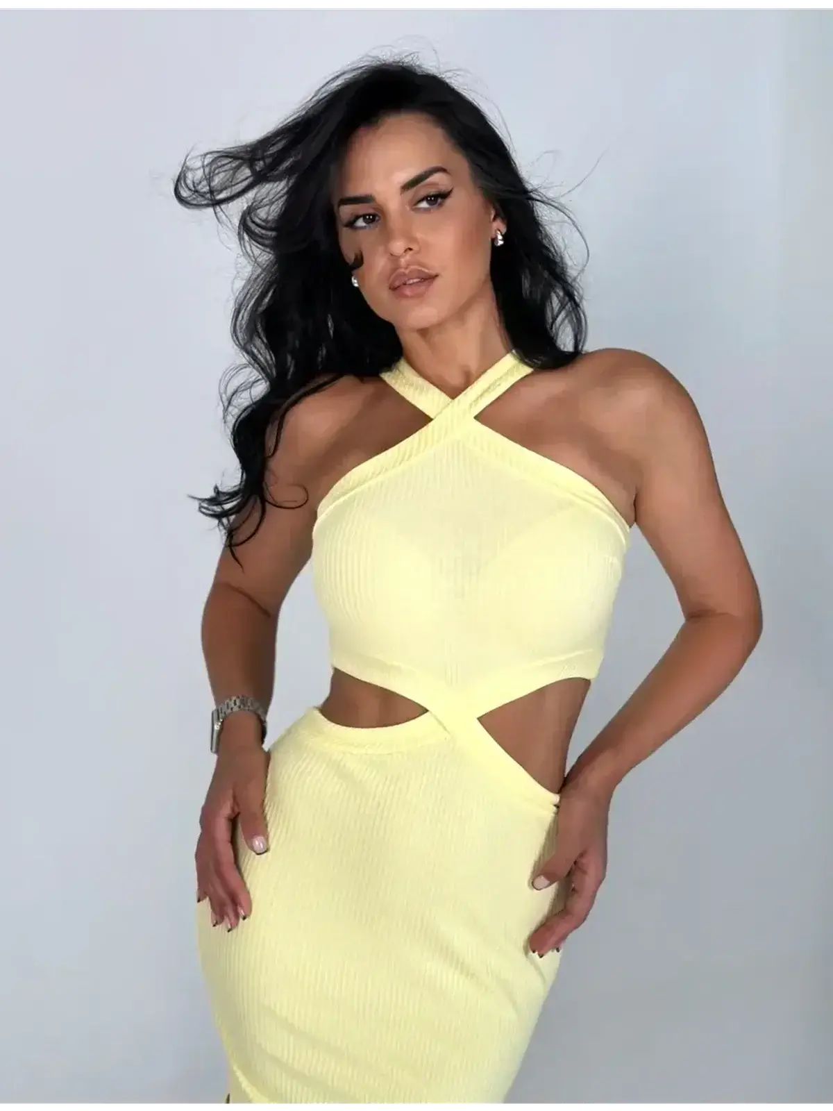 Model showcasing Sunlace Midi Dress in pastel yellow with sculptural cutouts and a modern design.