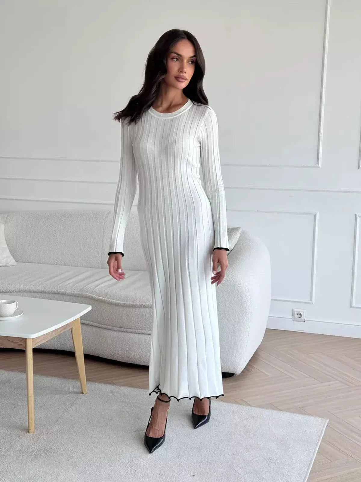 Model showcasing the Ivory Grace Maxi Dress, a fitted white dress with ribbed texture and ruffle trim, perfect for elegant occasions.