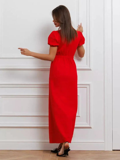 Back view of a woman in a bold red maxi dress featuring puff sleeves and a tie-front detail, exuding elegance.