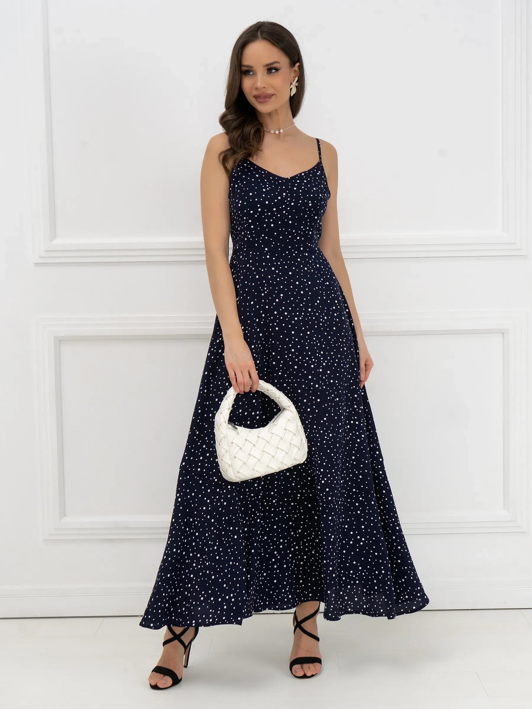 Noir Dots Maxi Dress featuring a flattering A-line cut and a micro-polka dot pattern, styled with a white handbag.