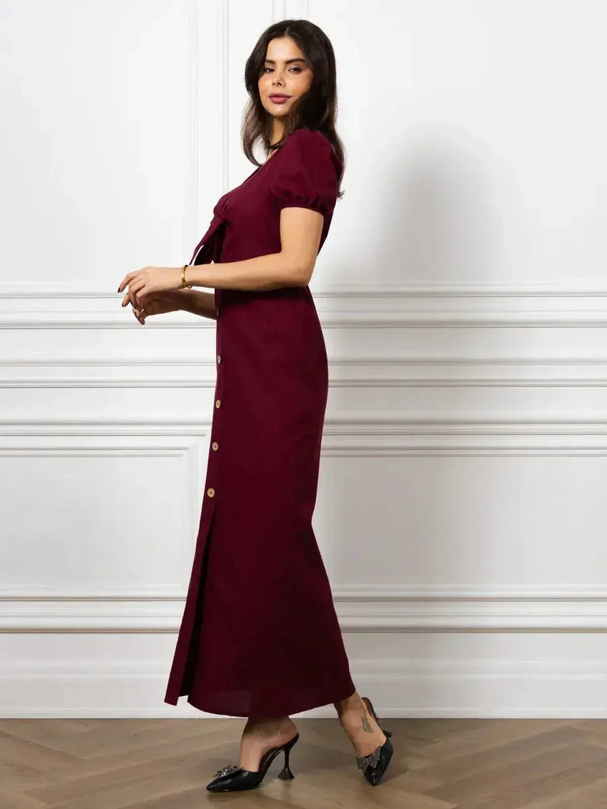 Elegant merlot maxi dress with front bow and button detail, highlighting a slim silhouette and puff sleeves.