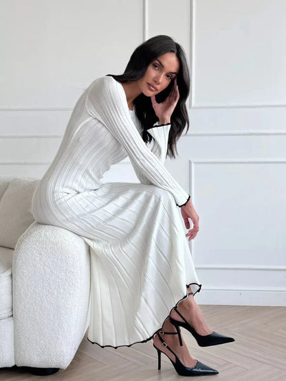 Ivory Grace Maxi Dress featuring elegant ribbed texture and ruffle trim, styled with black heels for a chic look.