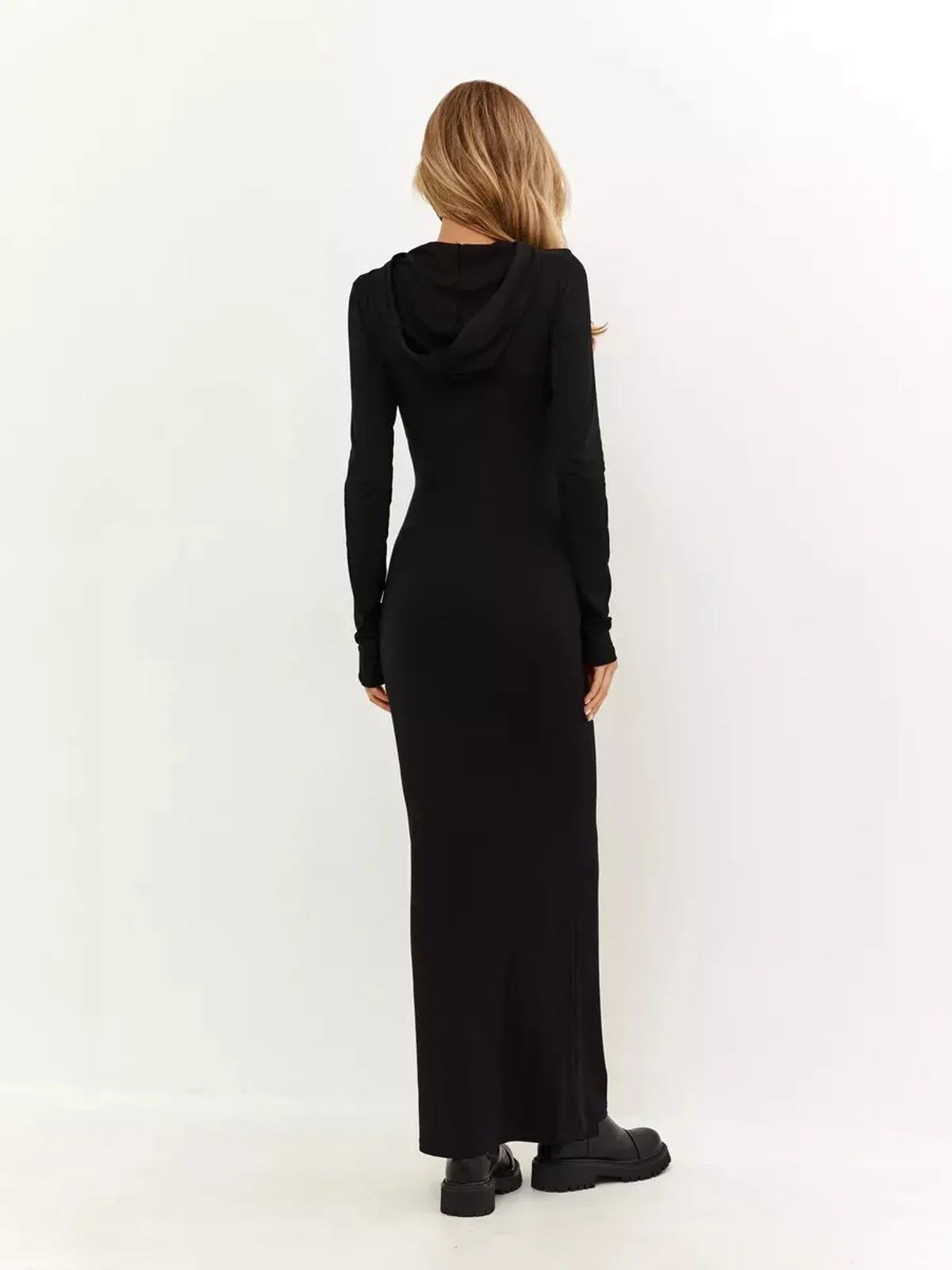 Rear view of a model wearing the Noir Maxi Dress, showcasing its minimalist design and hood detail in sleek black fabric.