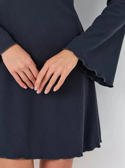 Close-up of hands on the flared sleeves and hem of the Graphite Grace mini dress, showcasing its textured fabric.