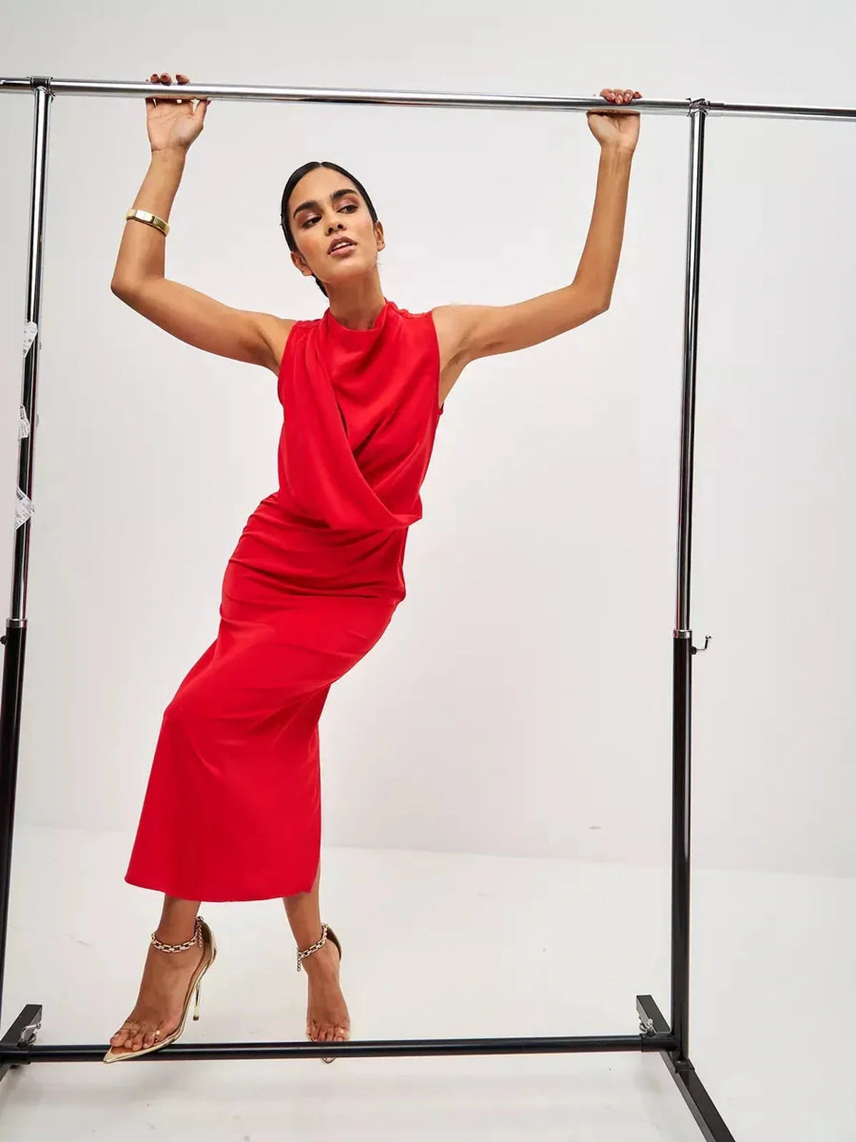 Model showcasing the elegant Red Drape Maxi Dress on a clothing rack, featuring a draped silhouette and vibrant red color.