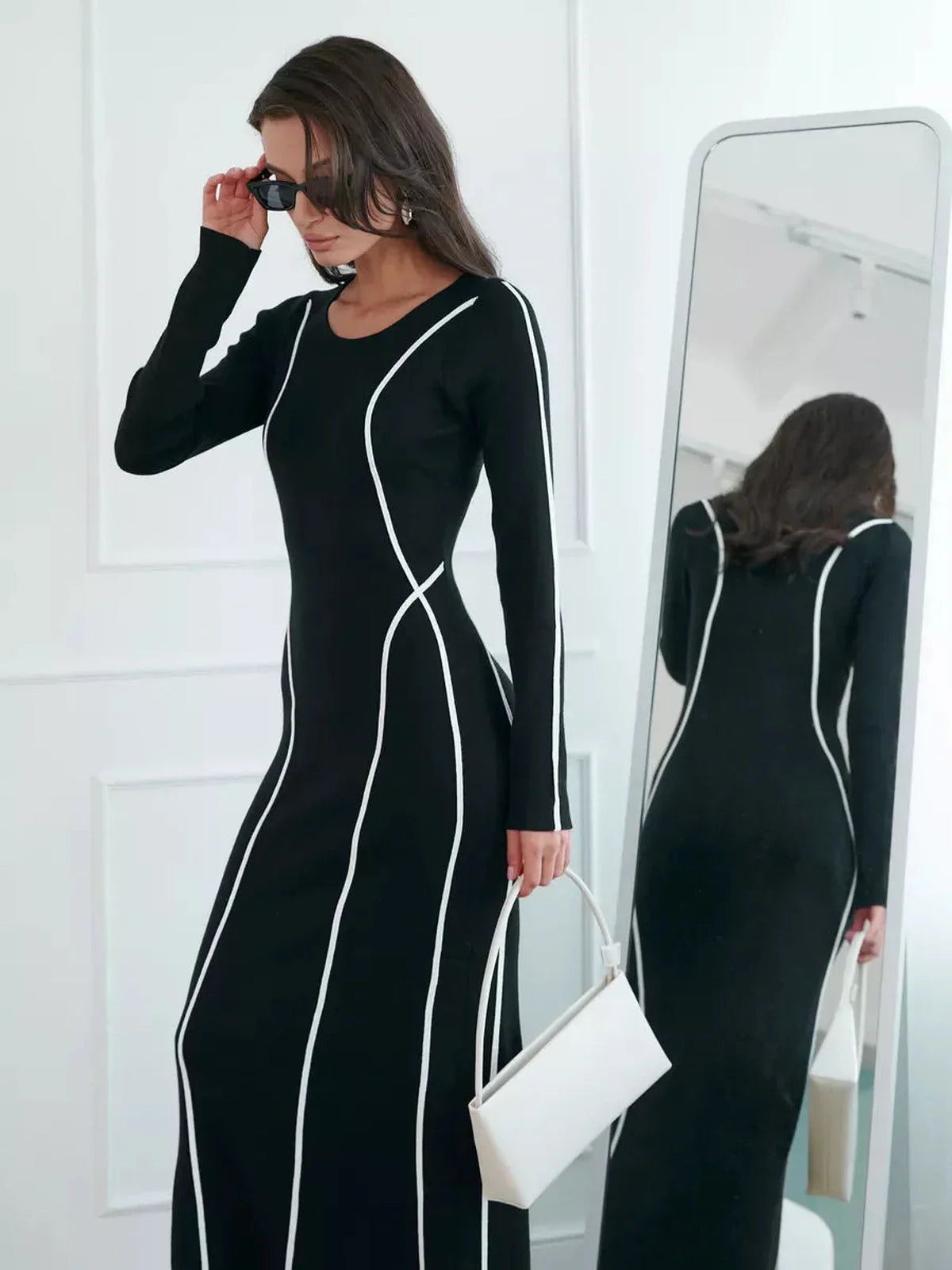 Model showcasing the Midnight Curve Maxi Dress with white piping, emphasizing an elegant silhouette and fashionable detail.