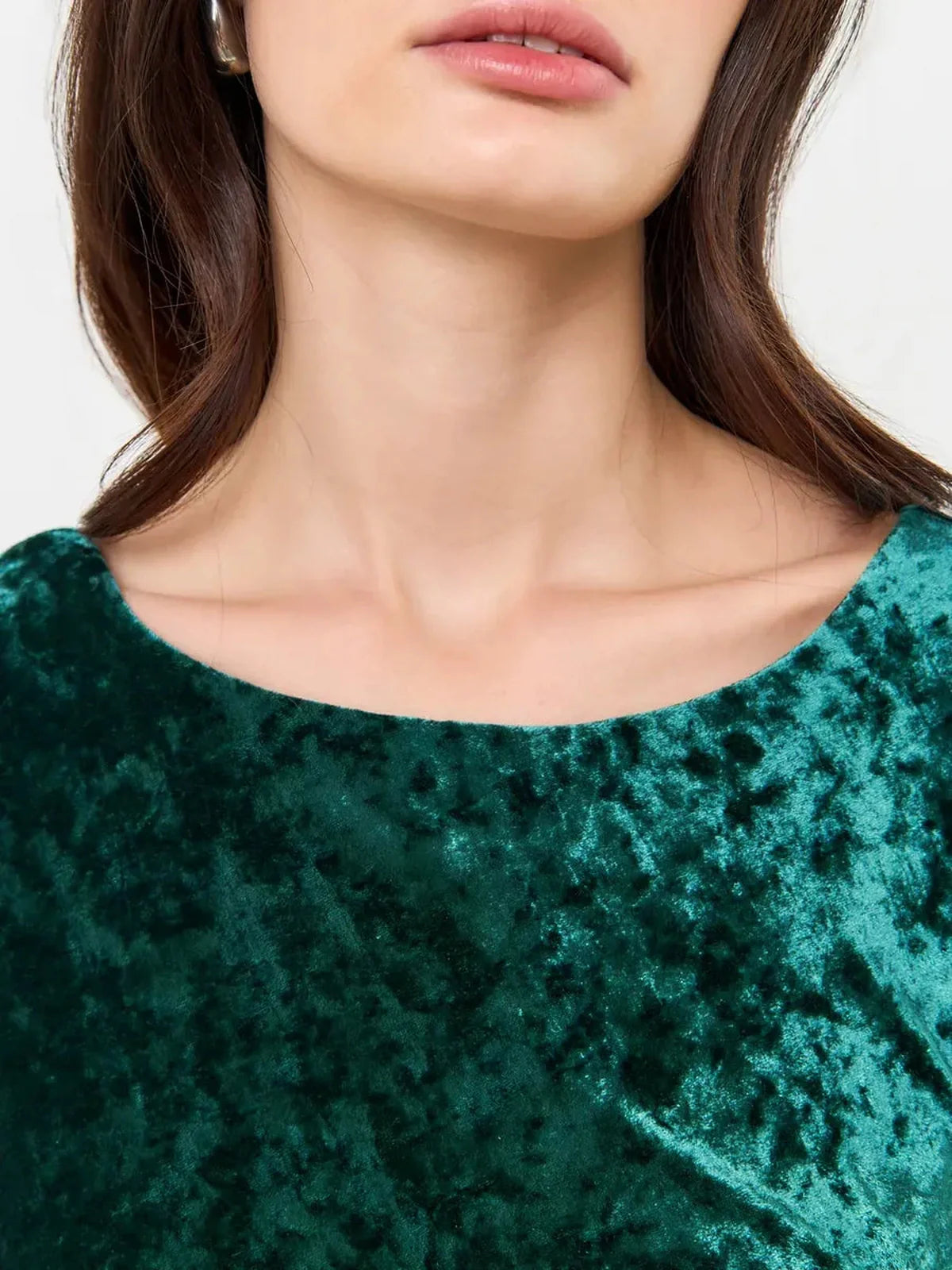 Close-up of a model showcasing the soft green velvet fabric of the Velvet Aura Maxi Dress with a boat neckline.