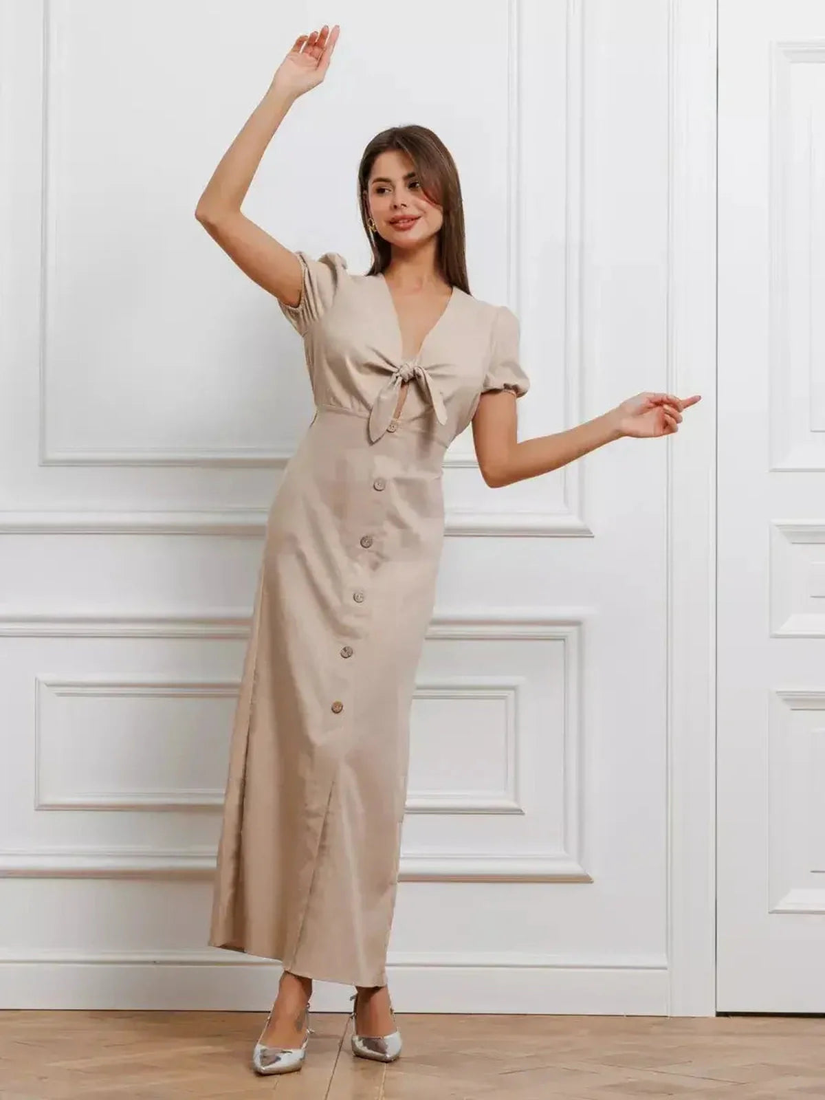 Chic woman wearing the Serene Bond Maxi Dress with puff sleeves and waist tie in a soft neutral hue, perfect for elegant occasions.