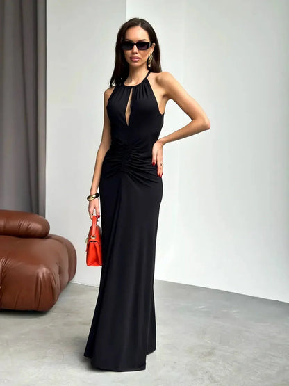 Elegant black halter maxi dress with draped detail, front keyhole cutout, and stylish accessories.