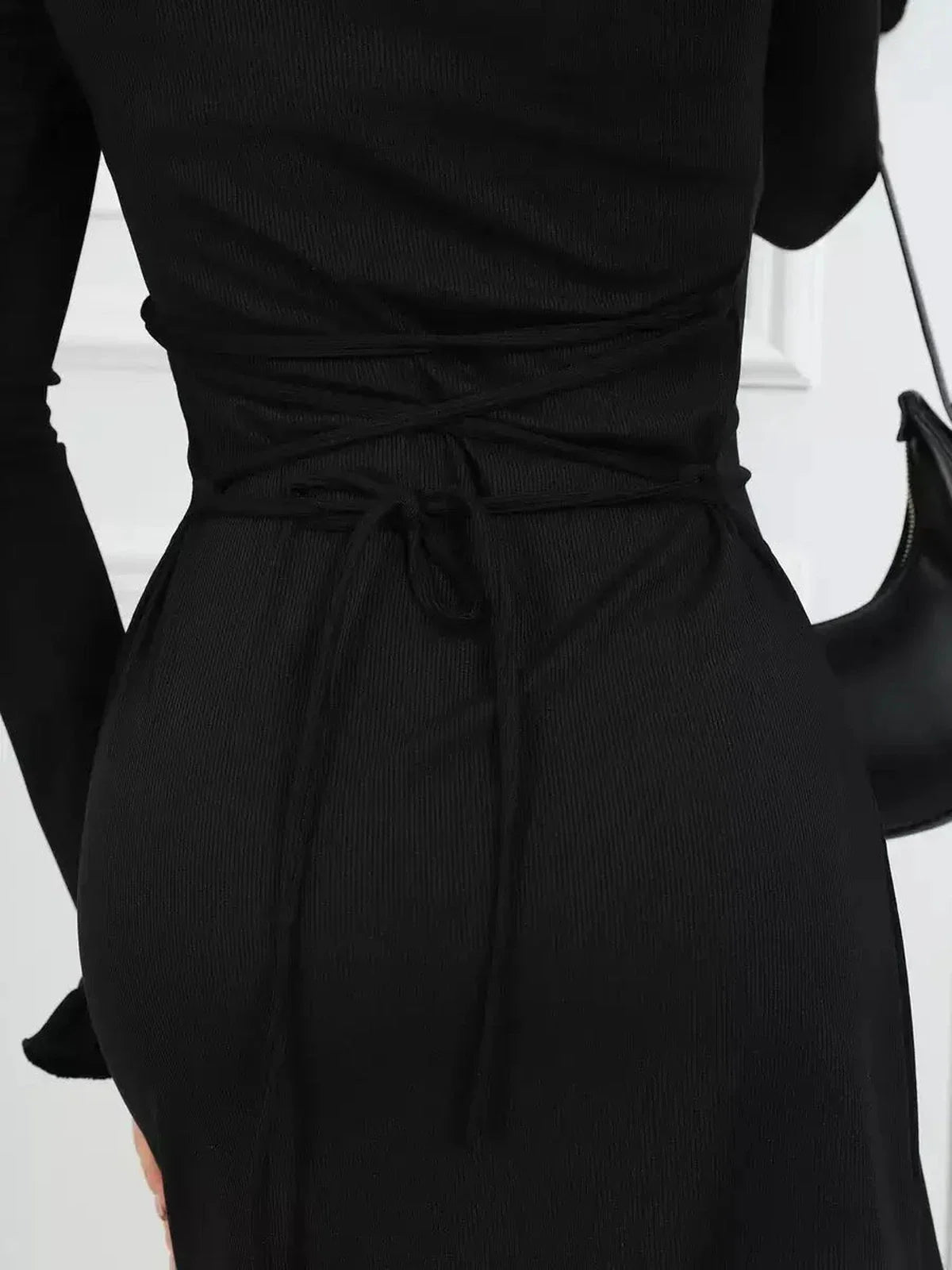 Detail of a black Velvet Lace Mini dress showcasing the curve-accentuating waist tie and elegant ribbed texture.