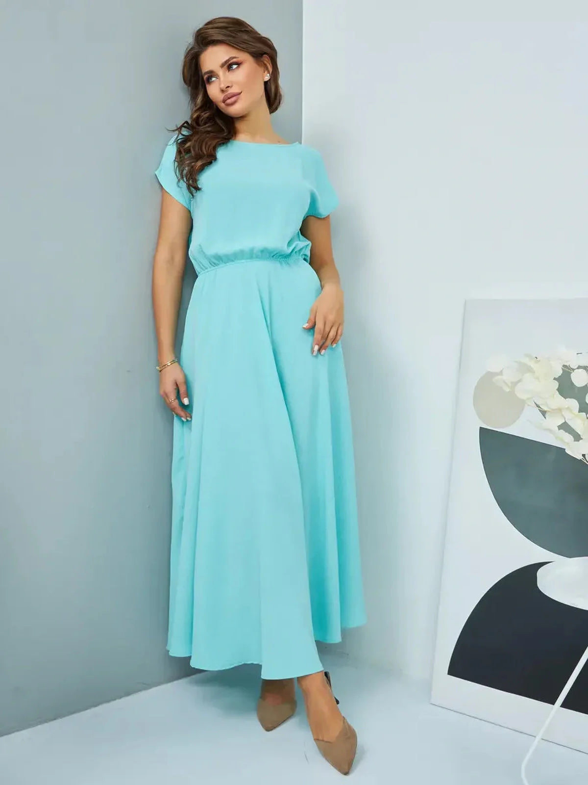 Model wearing a light blue maxi dress, showcasing elegant draping and a refined silhouette, perfect for evening wear.