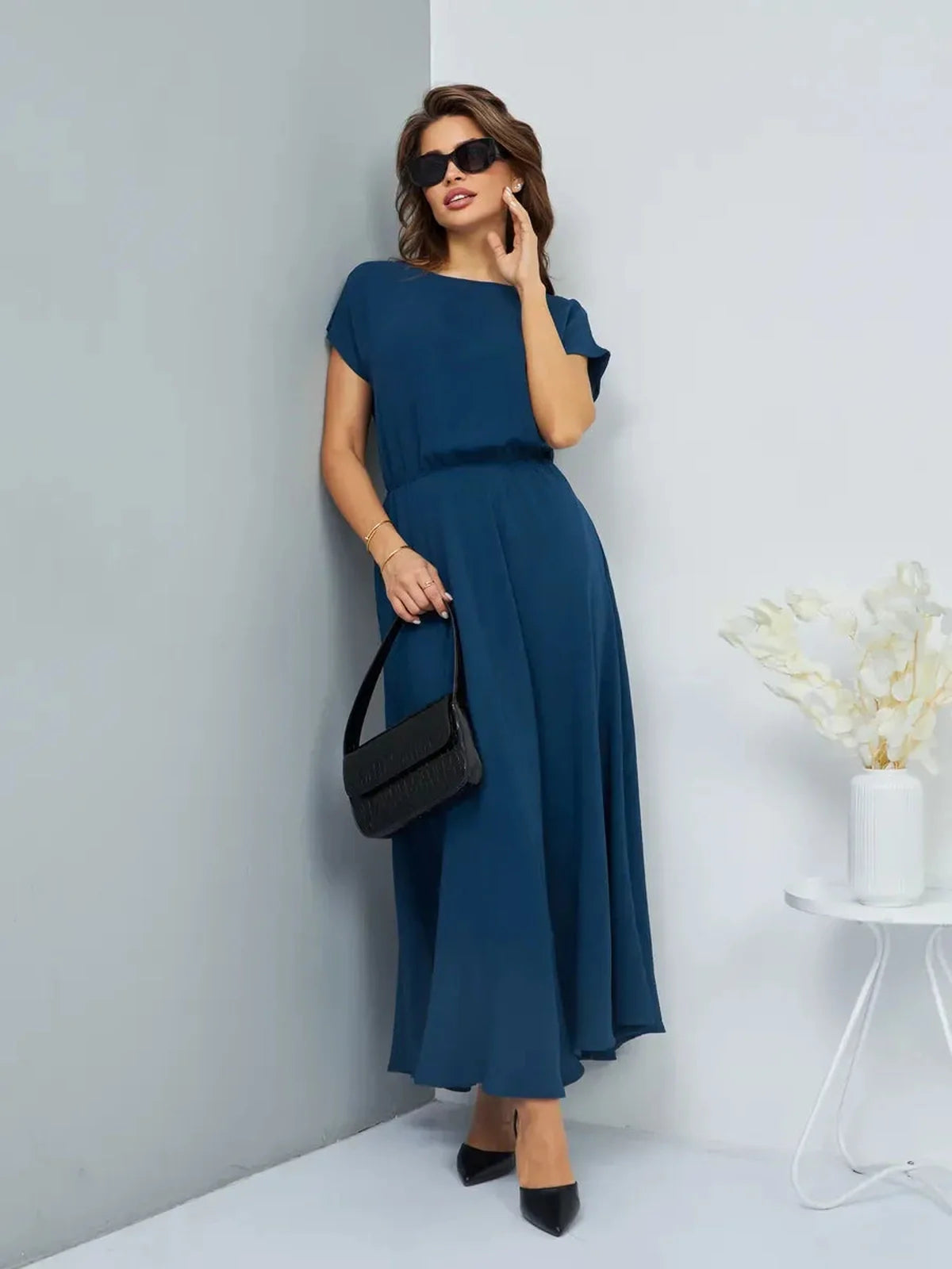 Model wearing a lightweight Verona Maxi Dress in teal, featuring a cinched waist and elegant ankle-grazing silhouette.