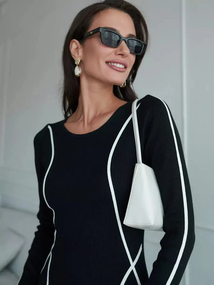 Model wearing Midnight Curve Maxi Dress with elegant white piping, accessorized with sunglasses and a chic white purse.