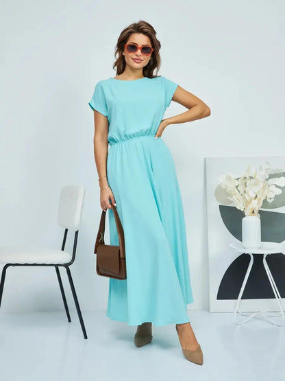 Model wearing a light blue maxi dress, styled with sunglasses and a brown handbag, showcasing effortless elegance.