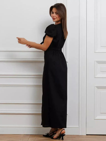Elegant woman in a black maxi dress with puff sleeves and tie-front detail, showcasing a refined silhouette.