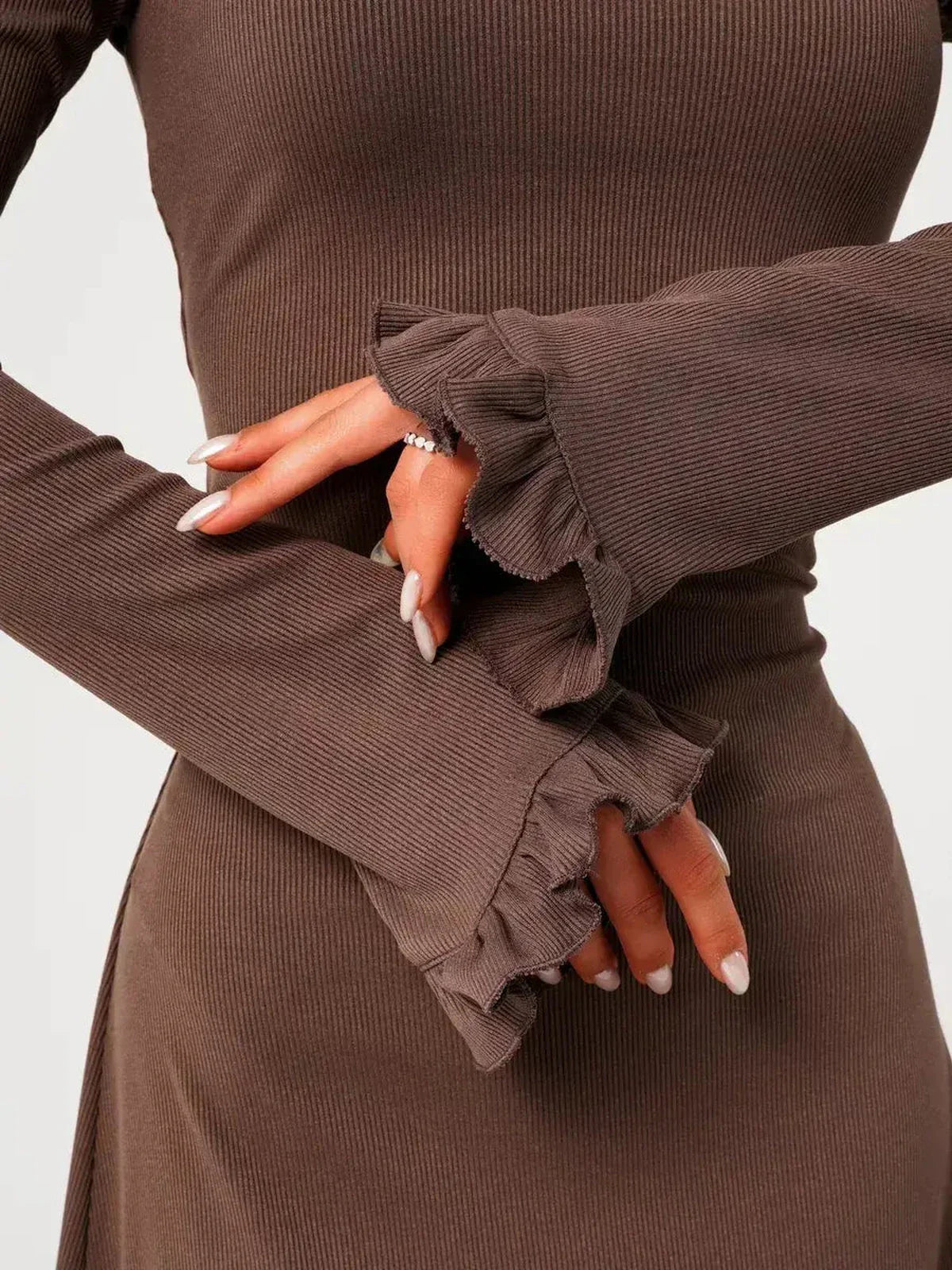 Close-up of hands showcasing flared ribbed knit cuffs of the Mocha Flare mini dress, highlighting its soft texture and romantic design.