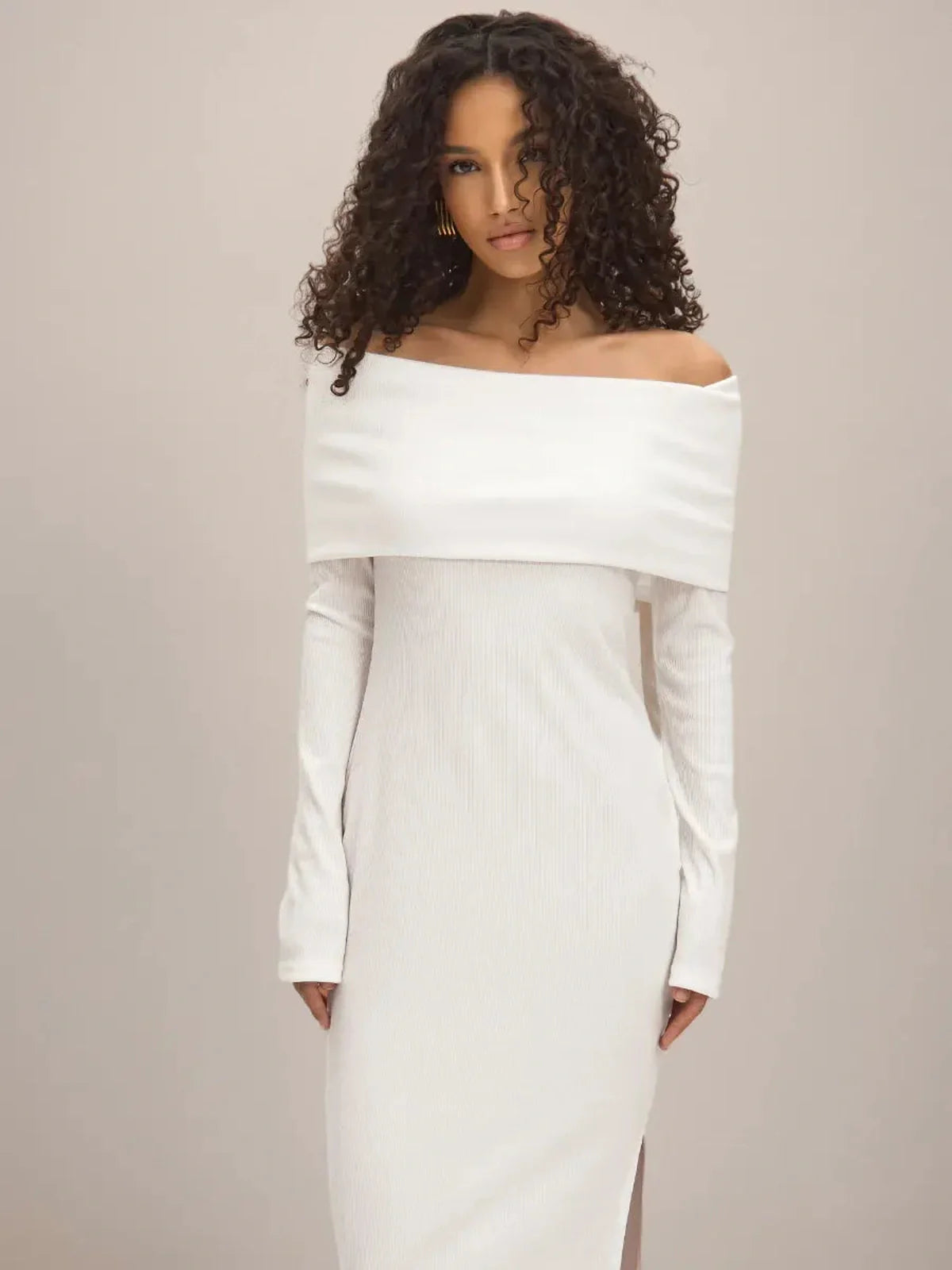 Model wearing the Sculpted Grace Maxi Dress featuring an off-shoulder design and side slit in a lightweight white fabric.