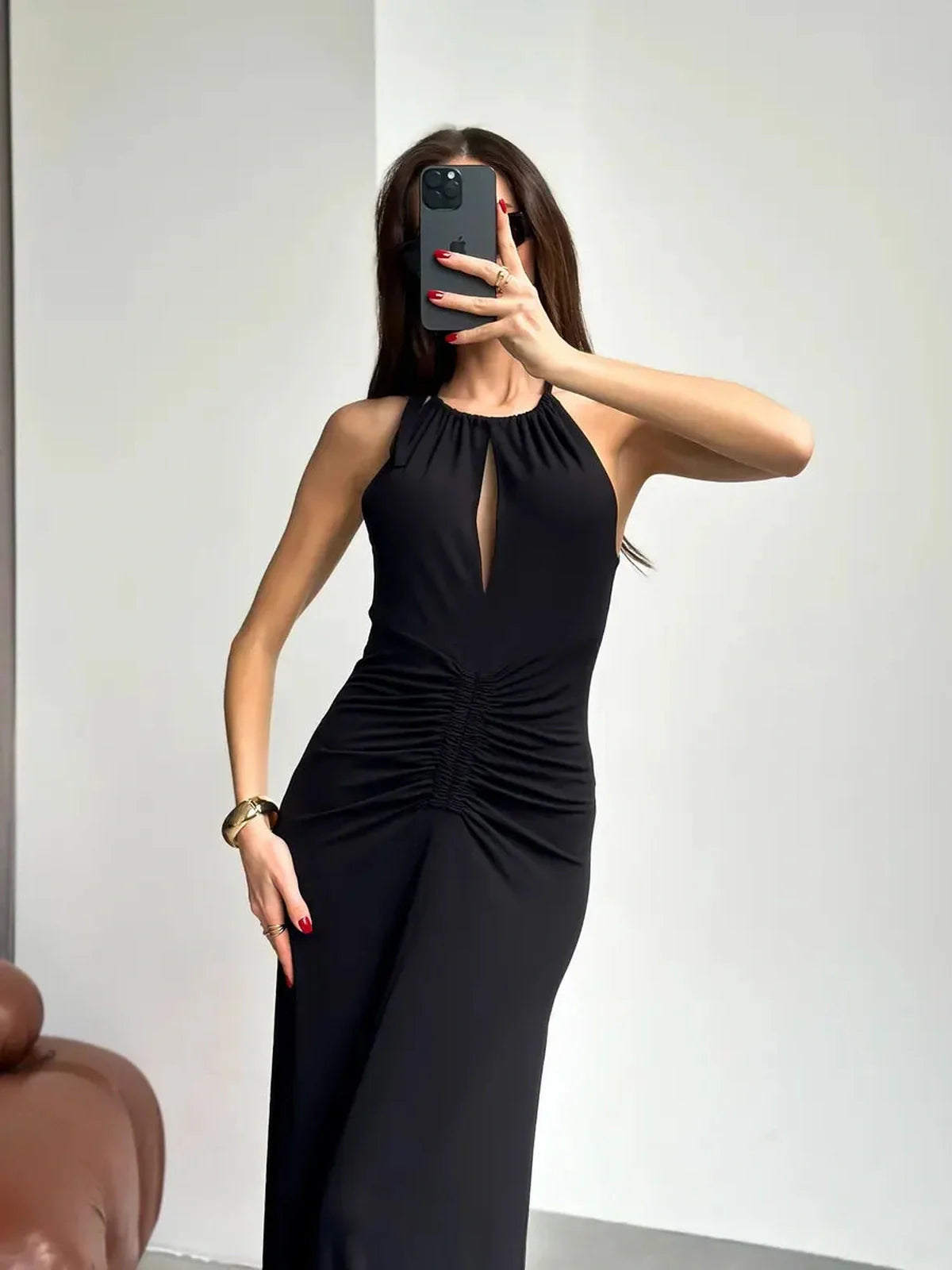 Elegant black maxi dress with halter neckline and front slit, showcasing ruching details and a sculpting effect.
