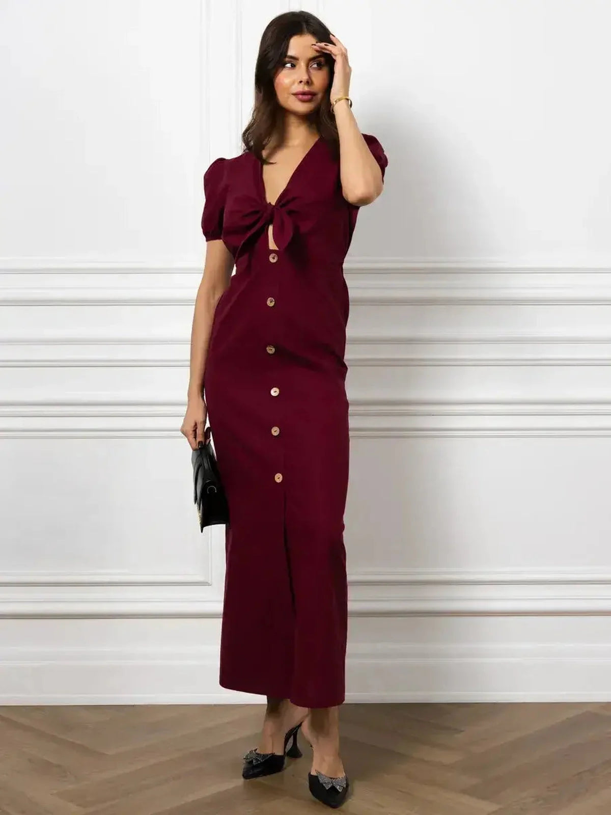 Elegant merlot maxi dress with front bow and button detail, featuring puff sleeves and a slim silhouette.