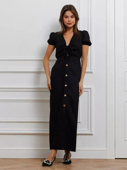 Model wearing the Maxi Dress Noir Belle, featuring a tie-front detail and contrast buttons, showcasing elegance and femininity.