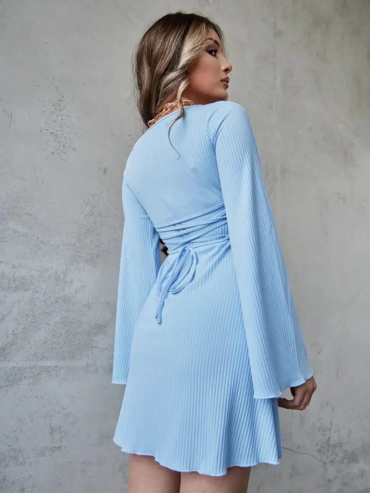 Model showcasing the Sky Flare blue ribbed mini dress with fluted sleeves and a delicate back tie.