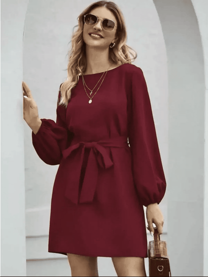 Elegant burgundy mini dress with long sleeves and cinched waist, perfect for wedding guests or cocktail events.