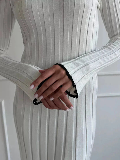 Close-up of hands in an ivory ribbed knit maxi dress showcasing elegant ruffle cuff details and chic style.
