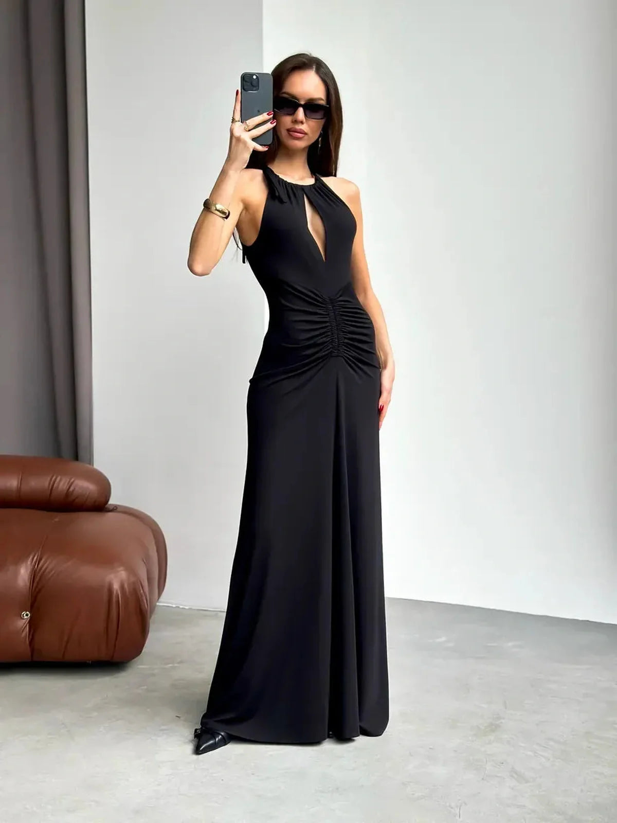 Model showcasing a stylish black maxi dress with ruched halter neckline and front slit, perfect for elegant occasions.