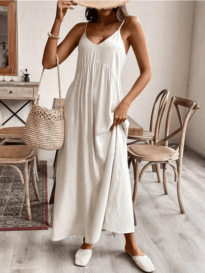 Model wearing a lightweight Serenity Maxi Dress in a soft hue, styled with a woven bag in a chic indoor setting.