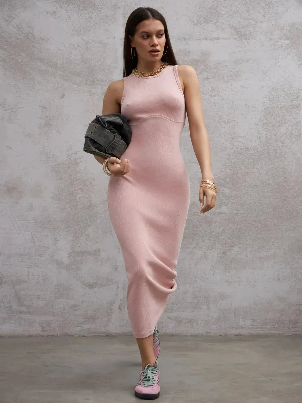 Model wearing a fitted blush pink maxi dress with a sleeveless design, styled for a modern romantic look.