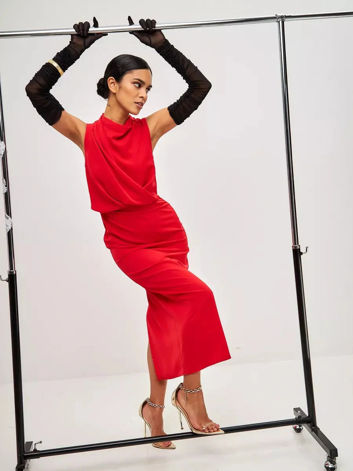 Model showcasing a red drape maxi dress with elegant draping and styled with long black gloves.
