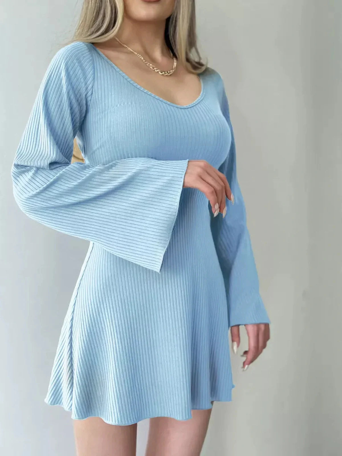 Model wearing a light blue ribbed knit mini dress with flared sleeves, perfect for summer occasions.