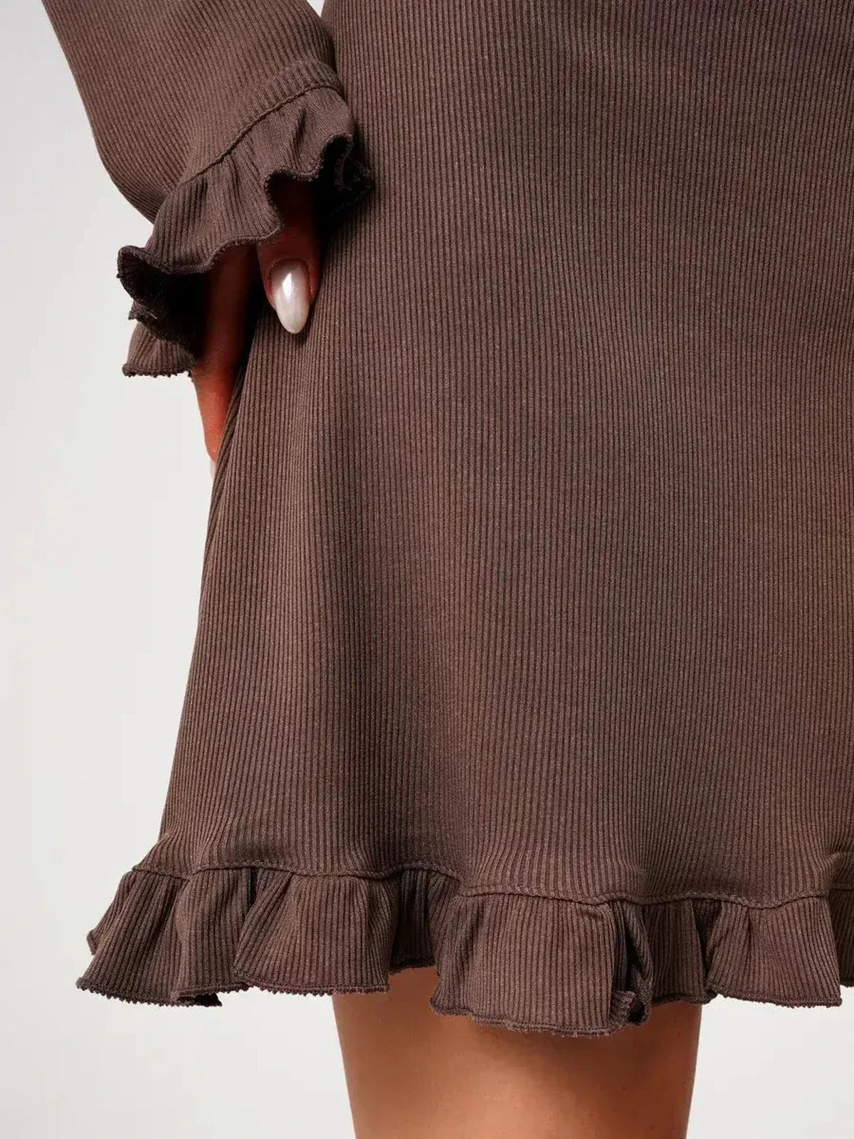 Close-up of Mocha Flare mini dress, showcasing ribbed knit fabric and delicate ruffled trim at cuffs and hem.