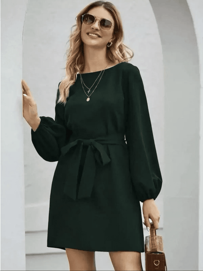 Model wearing an elegant emerald green mini dress with long sleeves and a belt, perfect for summer and special occasions.