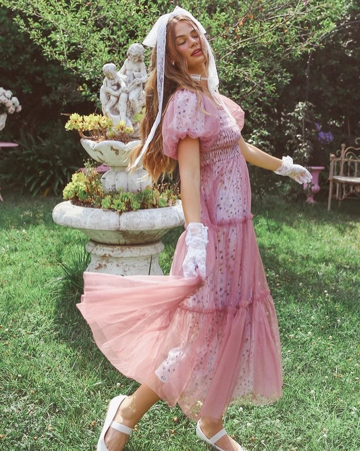 Model wearing a flowy pink maxi dress with a mesh overlay, perfect for summer occasions and weddings.